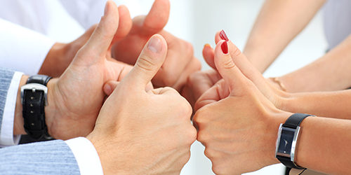 Close-up of business team holding their thumbs up
