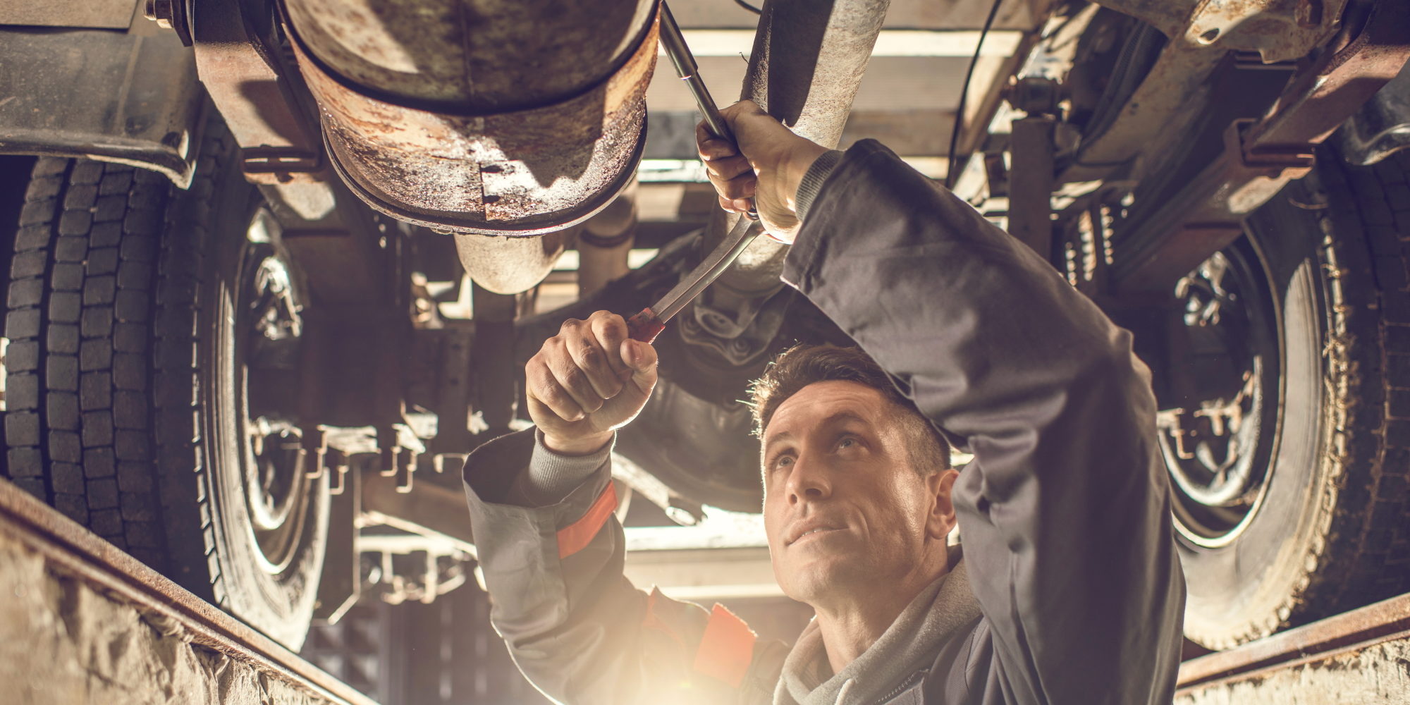 Mid adult auto mechanic working on a chassis in auto repair shop.